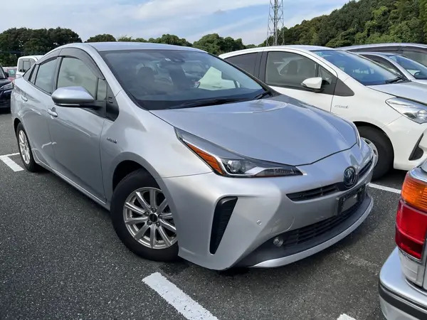 2. A silver Toyota Prius is parked in a busy parking lot, with several other cars visible in the background.